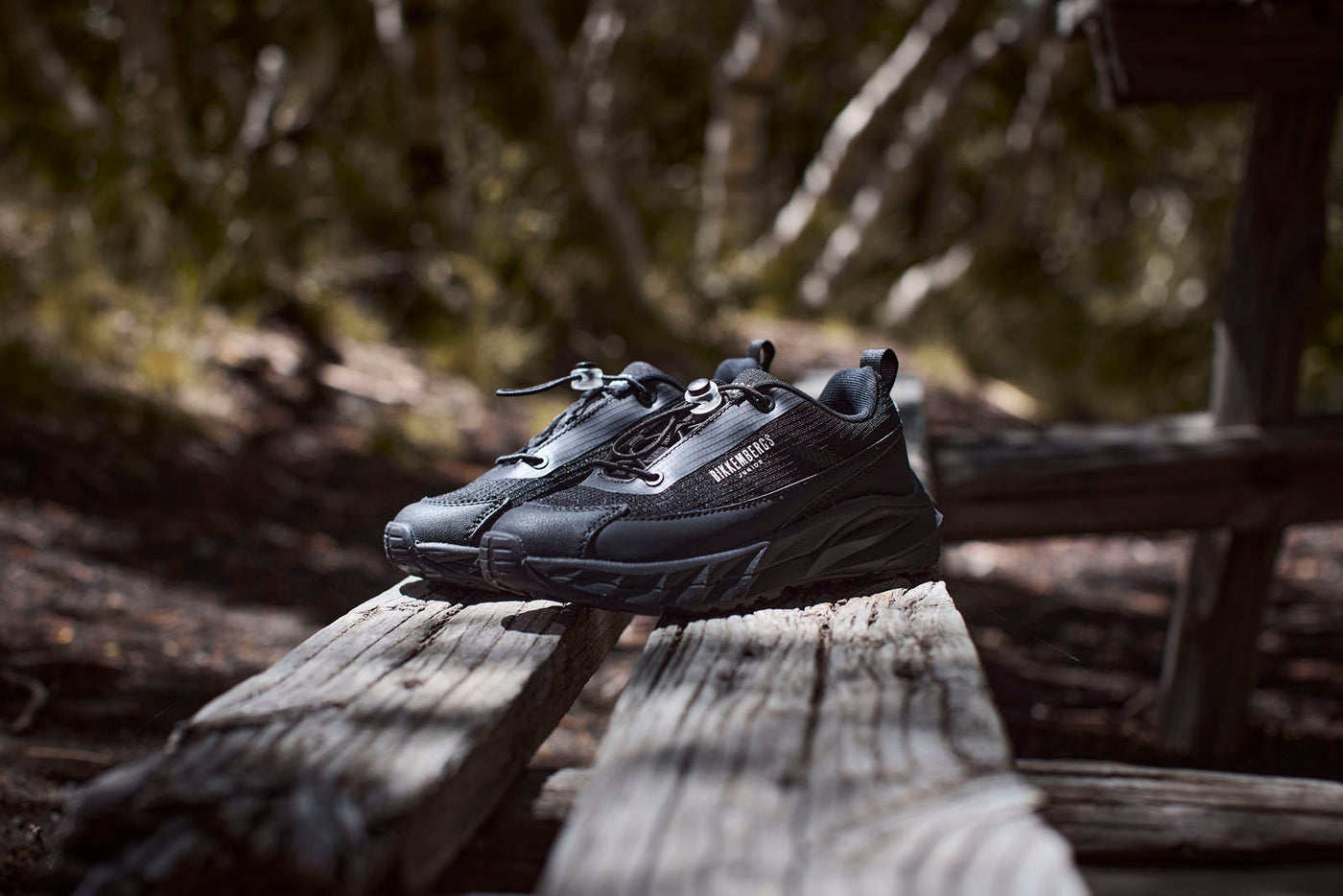 Sneakers nere Bikkembergs appoggiate su una panchina di legno all’aperto, illuminate da una luce naturale che ne mette in risalto i dettagli sportivi e il design robusto.
